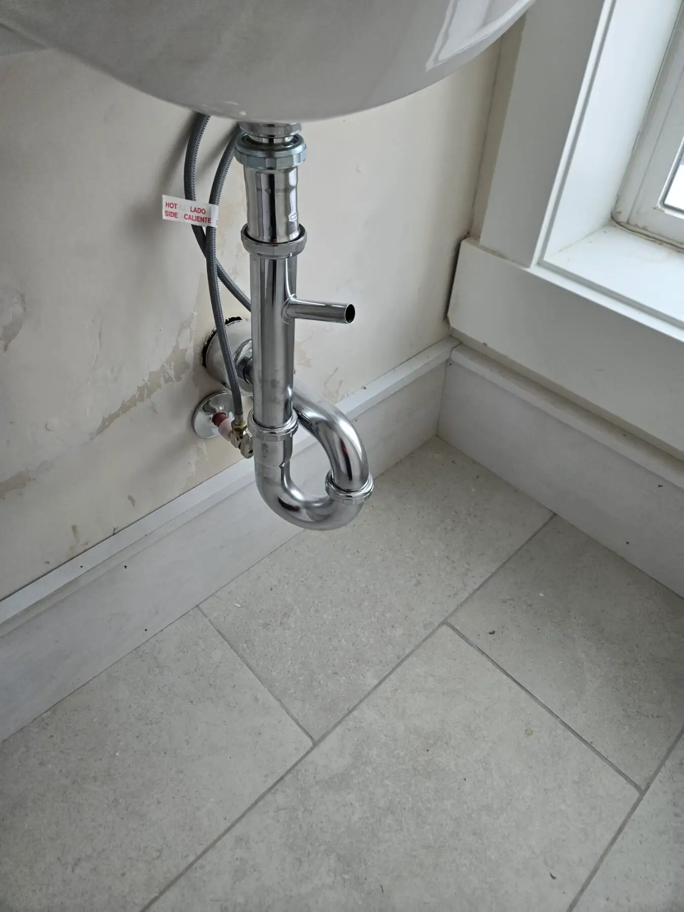 Chrome P-trap and supply lines under a bathroom sink after plumbing repair