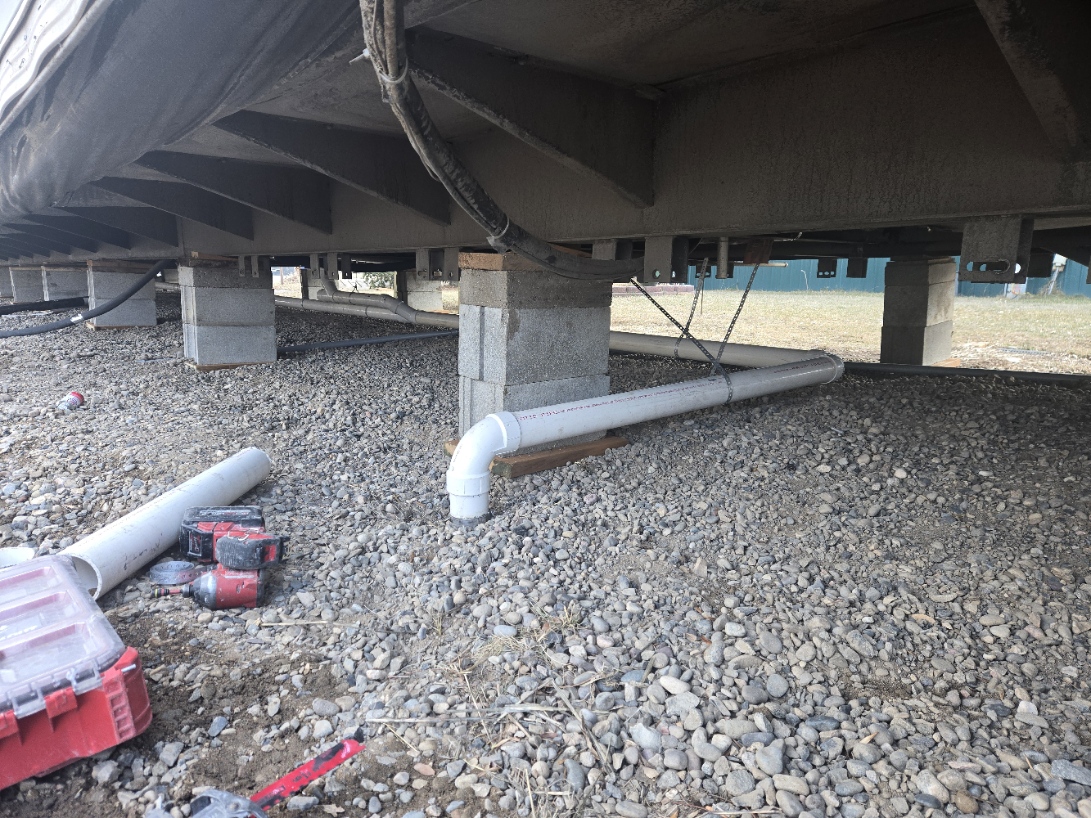 New PVC sewer line running under a home on gravel
