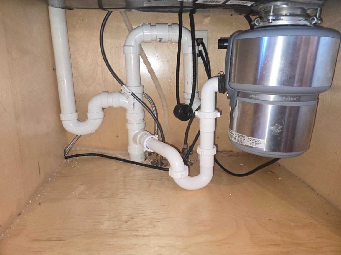 Kitchen sink drain lines and garbage disposal under a cabinet